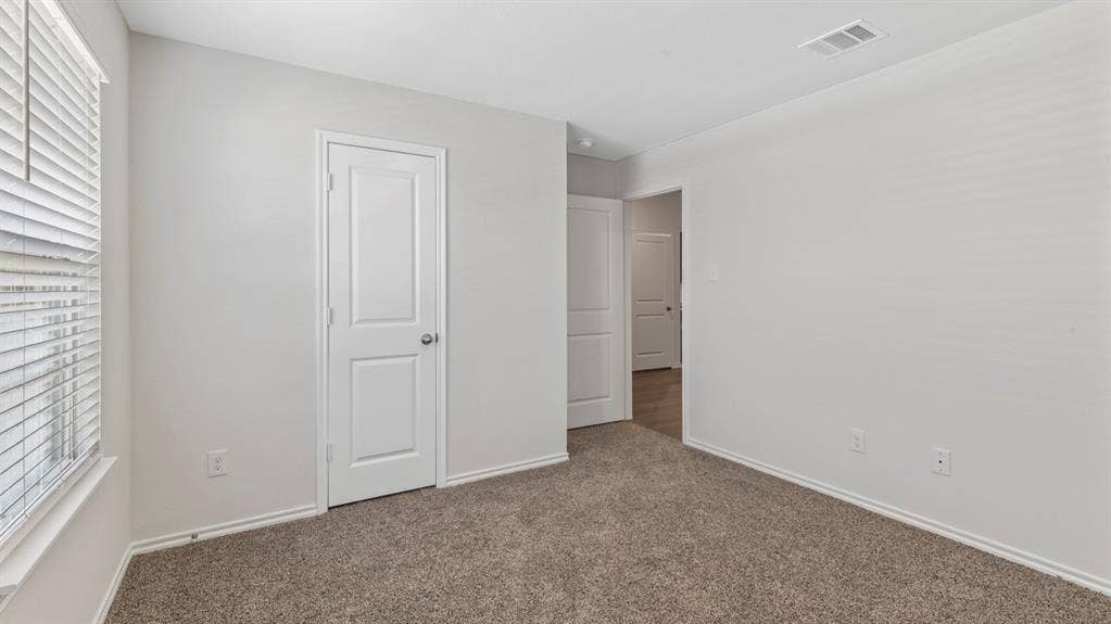 401 Banner Avenue, Royse City, TX 75189 Carpeted room featuring a window with horizontal blinds, white baseboards, and two paneled interior doors