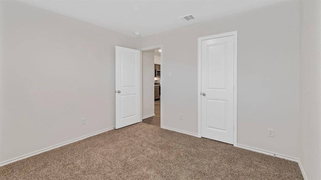 401 Banner Avenue, Royse City, TX 75189 Carpeted room featuring light gray walls, white baseboards, and two white paneled doors