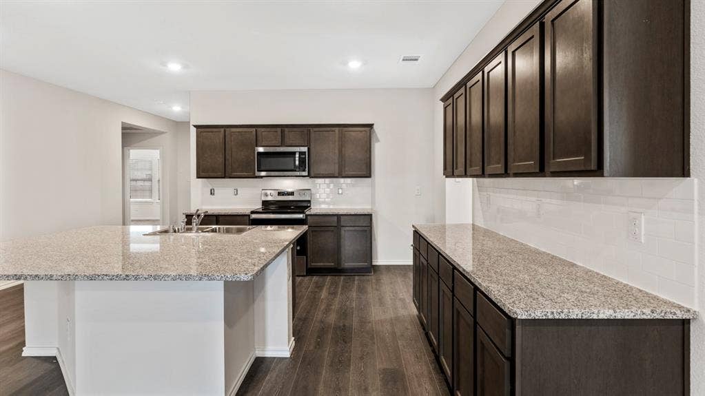 401 Banner Avenue, Royse City, TX 75189 Kitchen featuring dark wood-finish cabinetry, light speckled countertops, a subway tile backsplash, and wood-finish flooring
