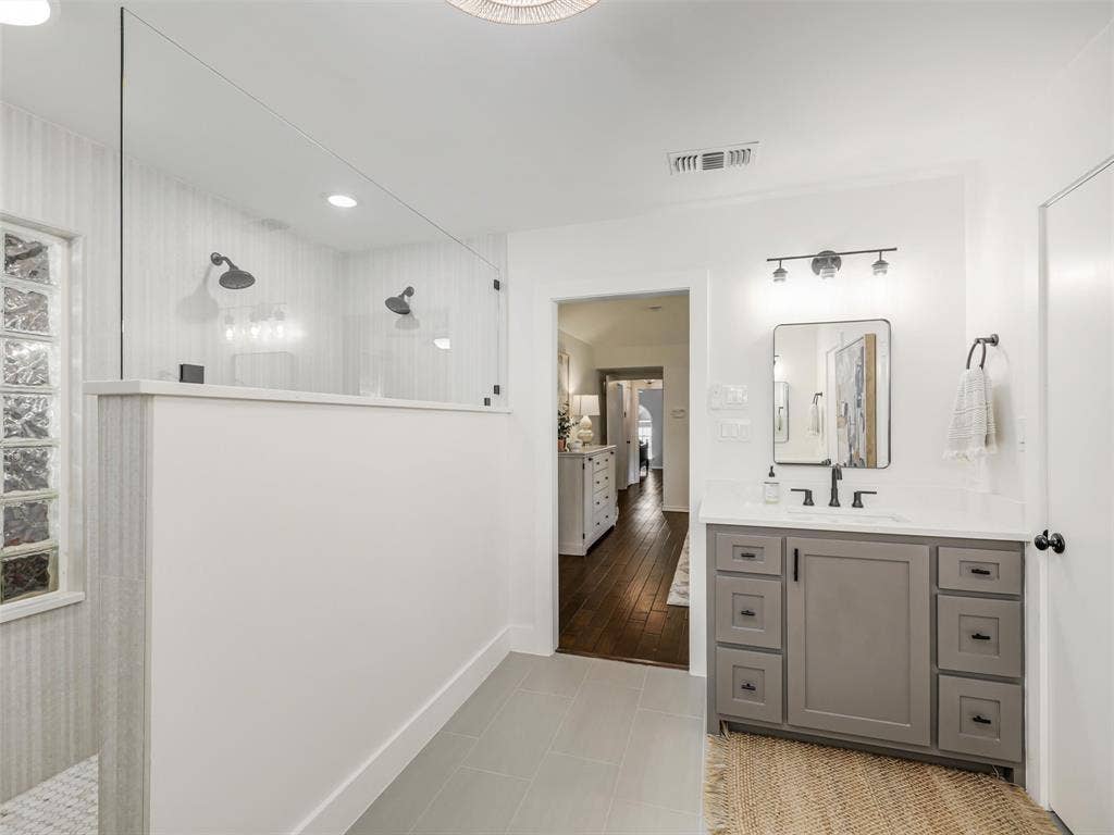 3617 Hackamore Court, Plano, TX 75023 Bathroom featuring a gray vanity with a white countertop, a black-framed mirror, and modern shower with dual heads.