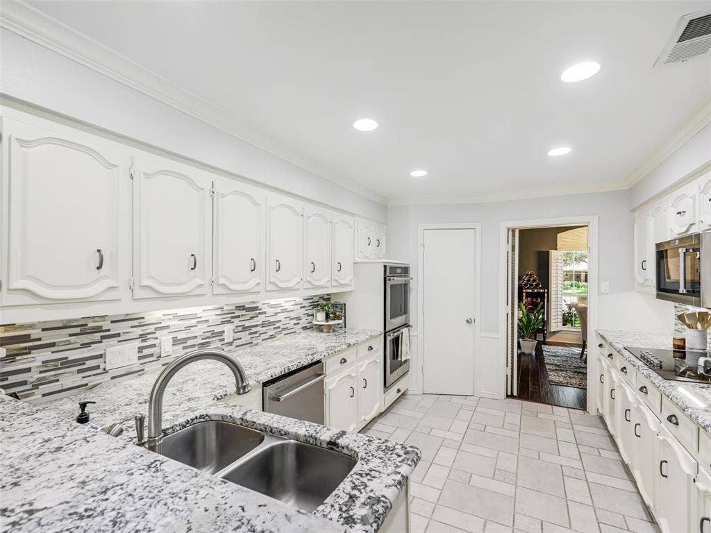 3617 Hackamore Court, Plano, TX 75023 Bright kitchen featuring white cabinetry, light-toned countertops, a mosaic tile backsplash, and recessed lighting