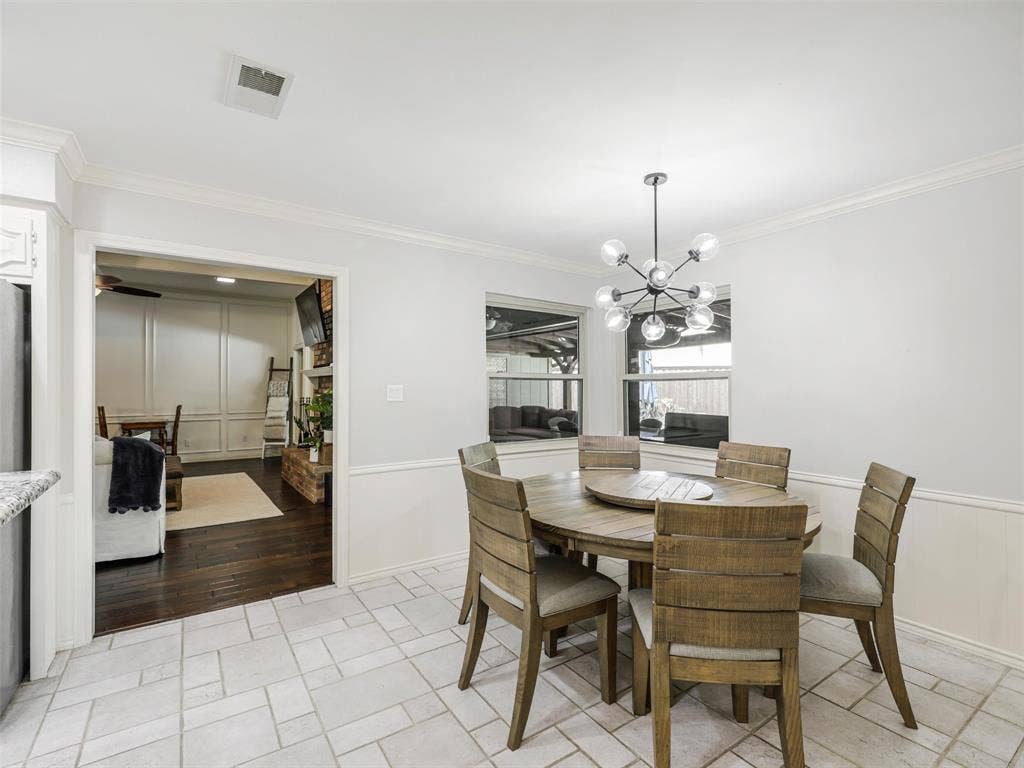 3617 Hackamore Court, Plano, TX 75023 Dining area featuring an open concept design, a contemporary multi-bulb chandelier, two large windows, white wainscoting, and tile flooring