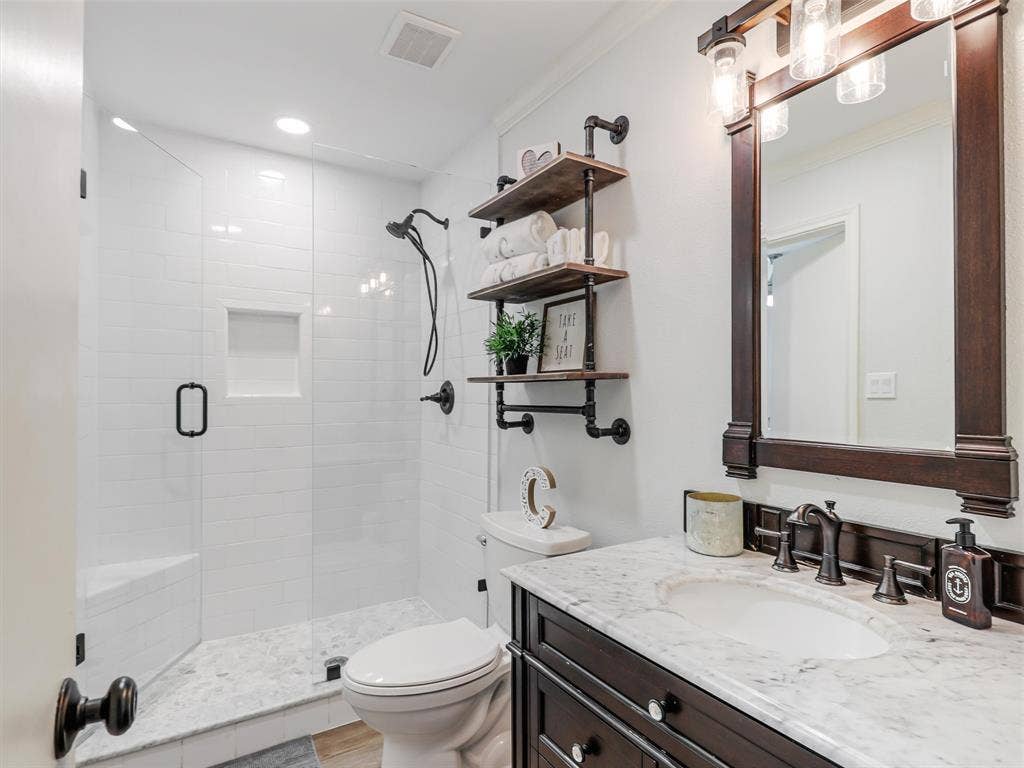3617 Hackamore Court, Plano, TX 75023 Bathroom featuring a glass-enclosed shower with white subway tile, an integrated shower bench, and a built-in niche
