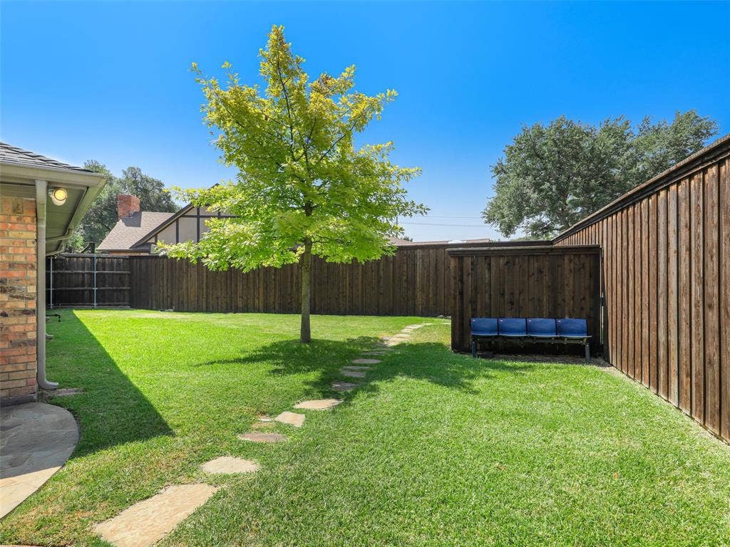 3617 Hackamore Court, Plano, TX 75023 Expansive backyard featuring a manicured lawn, established tree, and stone pathway