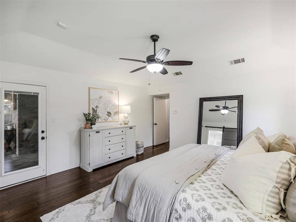 3617 Hackamore Court, Plano, TX 75023 Spacious primary bedroom featuring hardwood flooring, ceiling fan with integrated lighting, and abundant natural light from door to back yard.