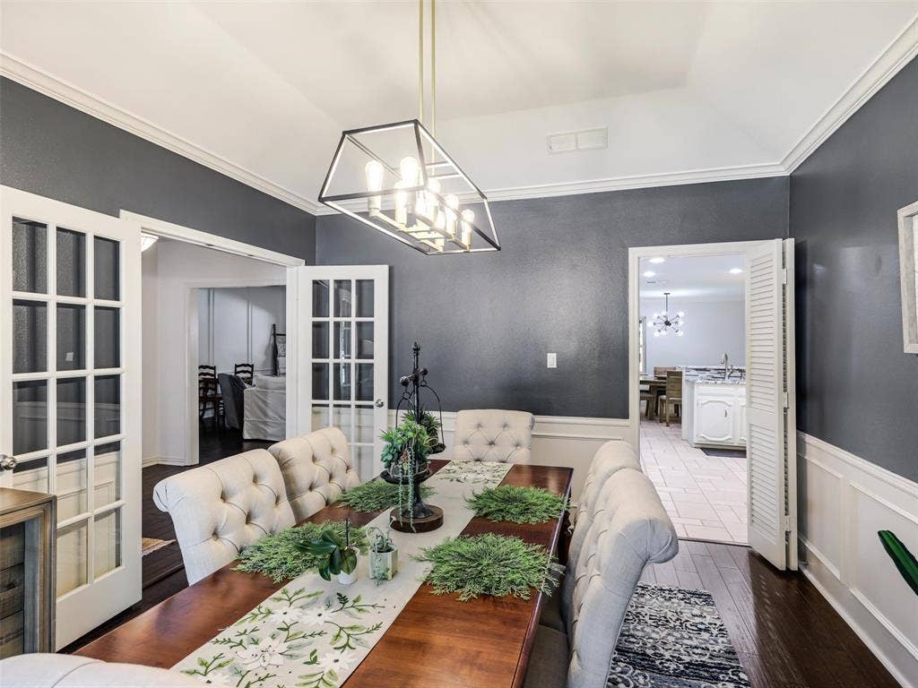 3617 Hackamore Court, Plano, TX 75023 Dining area featuring dark wood-finish flooring, a contemporary linear chandelier, and wainscoting with crown molding