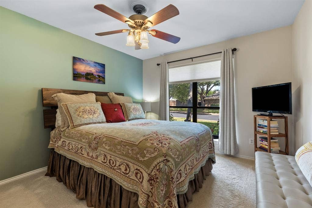 6803 Fernshaw Drive, Dallas, TX 75248 Recessed lighting with a ceiling fan, accent wall, wood-finish headboard, window with privacy blinds, and carpeted flooring