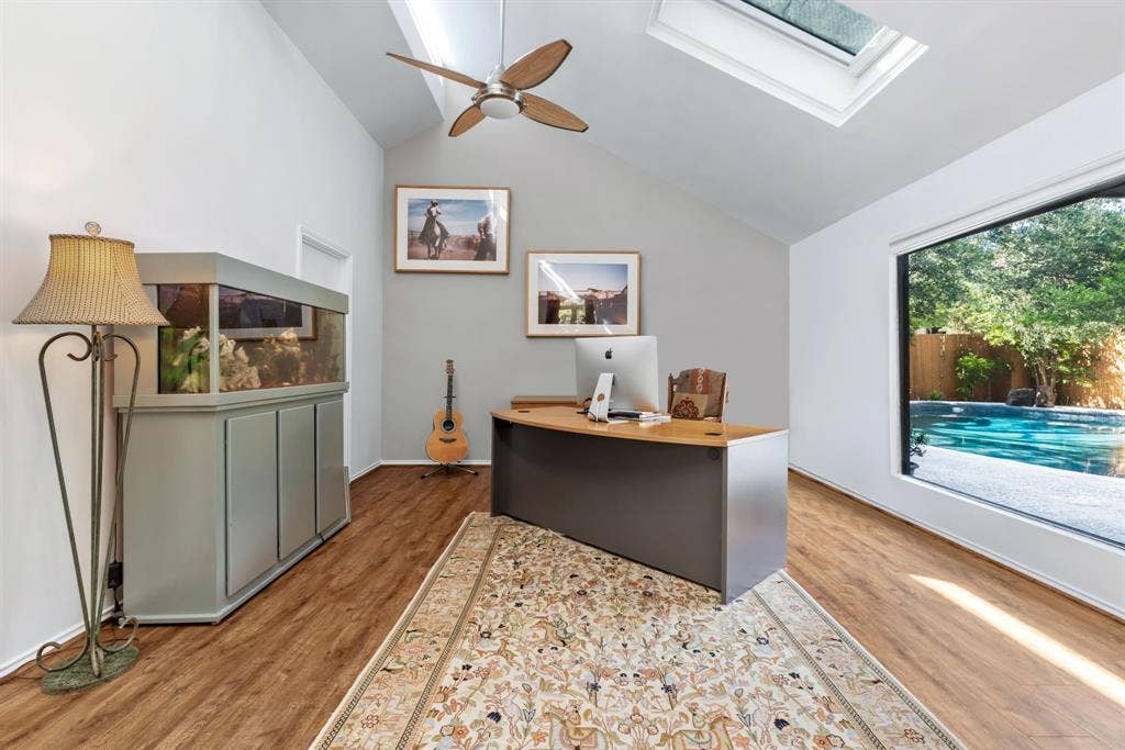 6803 Fernshaw Drive, Dallas, TX 75248 Vaulted ceiling with skylight, wood-finish flooring, ceiling fan, and large picture window overlooking a swimming pool