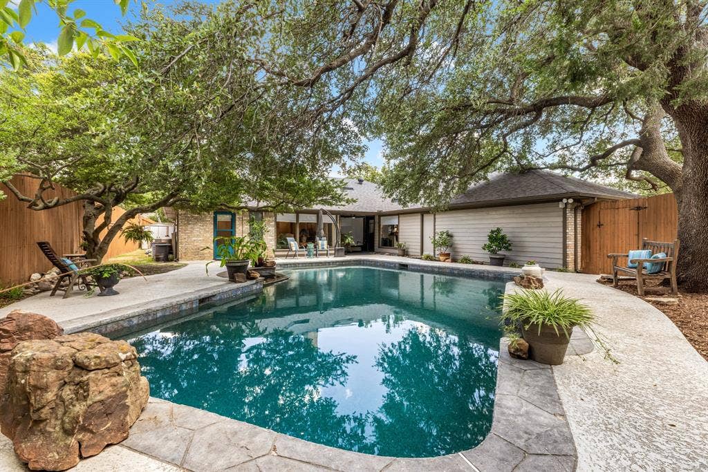 6803 Fernshaw Drive, Dallas, TX 75248 Swimming pool with flagstone coping, surrounding concrete patio, and mature trees providing shade