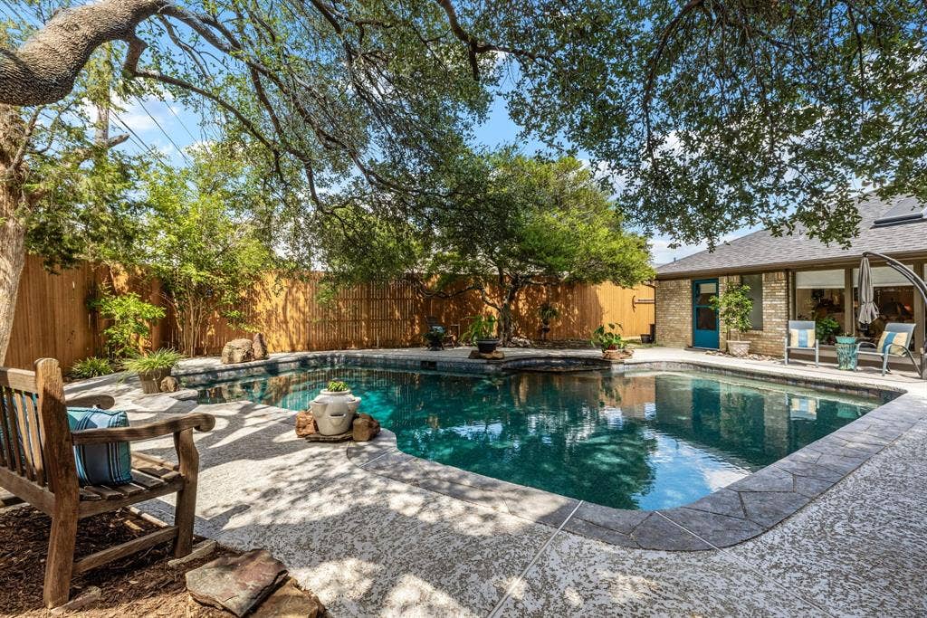 6803 Fernshaw Drive, Dallas, TX 75248 Private backyard oasis featuring a swimming pool with stone coping, a spacious patio area, mature trees, and a privacy fence