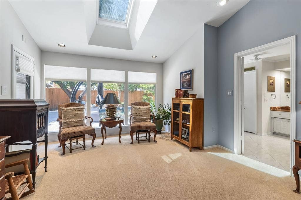6803 Fernshaw Drive, Dallas, TX 75248 Vaulted ceiling with skylight, recessed lighting, expansive window wall, light-toned carpeting, and a doorway opening to a tiled space