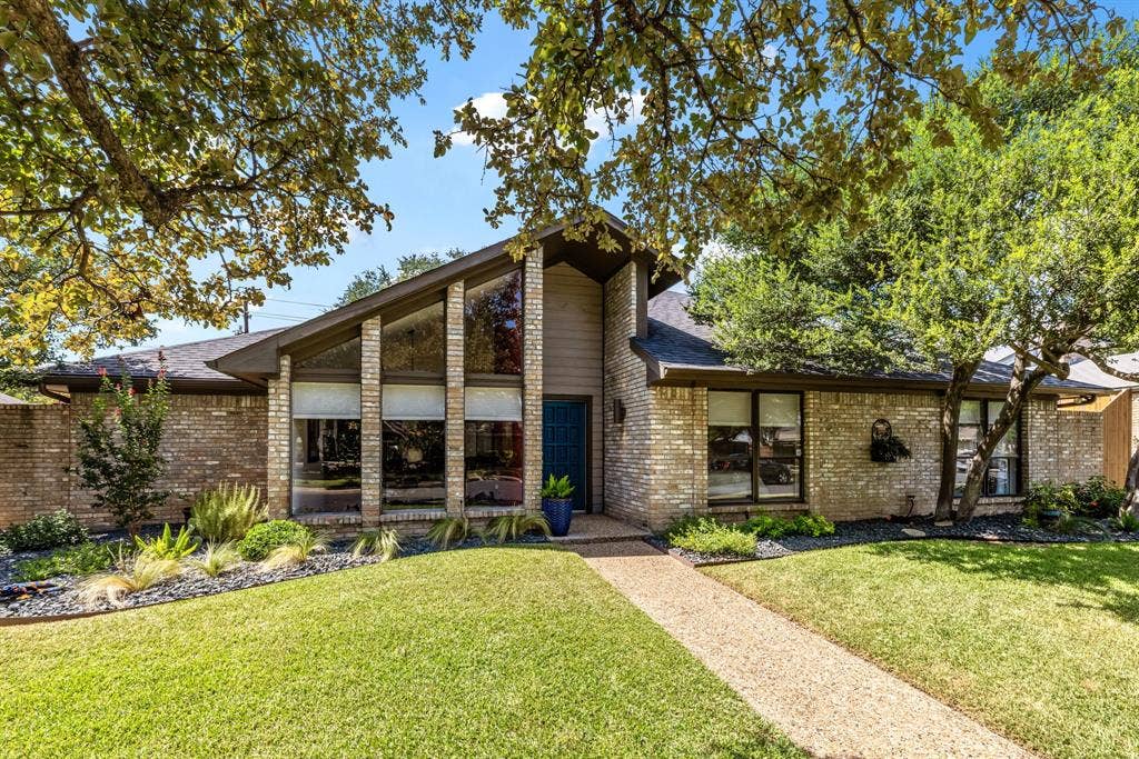 6803 Fernshaw Drive, Dallas, TX 75248 Brick exterior with a prominent A-frame architectural feature, expansive front windows, and mature trees providing shade