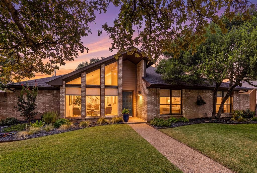 6803 Fernshaw Drive, Dallas, TX 75248 Brick exterior with a prominent A-frame architectural feature, extensive front-facing window panels, mature landscaping, and a defined walkway