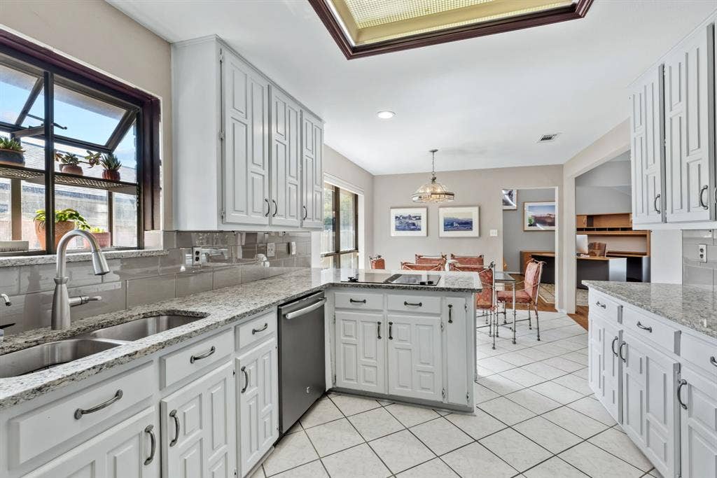 6803 Fernshaw Drive, Dallas, TX 75248 Kitchen featuring white cabinetry, light-toned countertops, a stainless steel sink, tile flooring, and a skylight