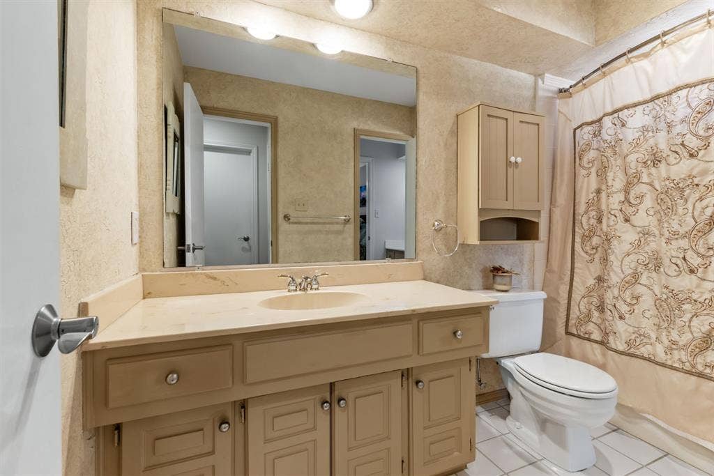 6803 Fernshaw Drive, Dallas, TX 75248 Vanity with an integrated sink and light-toned countertop, accompanied by a wall-mounted medicine cabinet, and a toilet