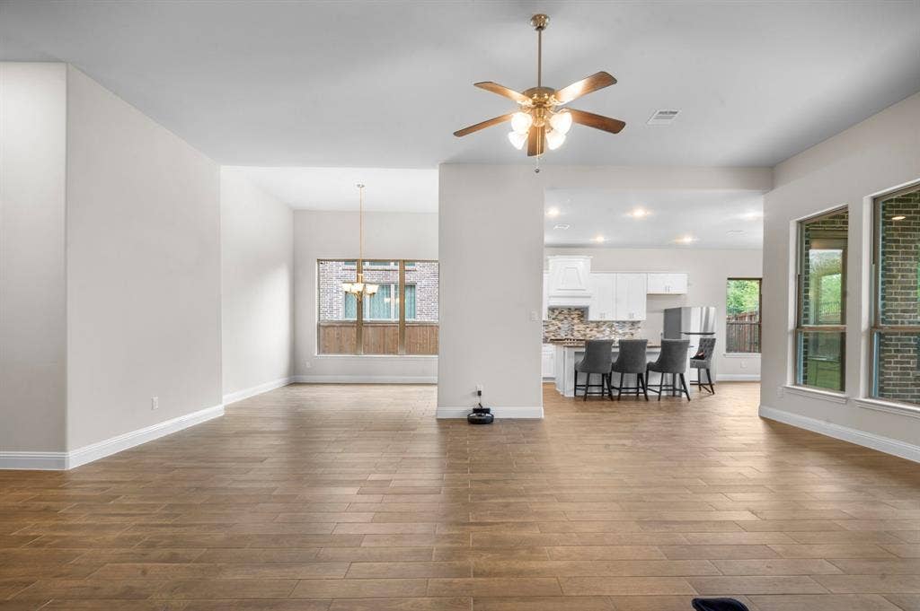16050 Talamore Lane, Frisco, TX 75035 Unfurnished living room with ceiling fan with notable chandelier and wood-type flooring