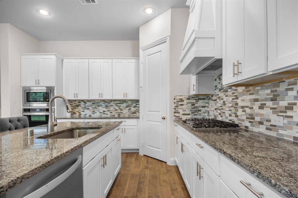 16050 Talamore Lane, Frisco, TX 75035 Kitchen with dark hardwood / wood-style flooring, stone countertops, stainless steel appliances, sink, and custom exhaust hood