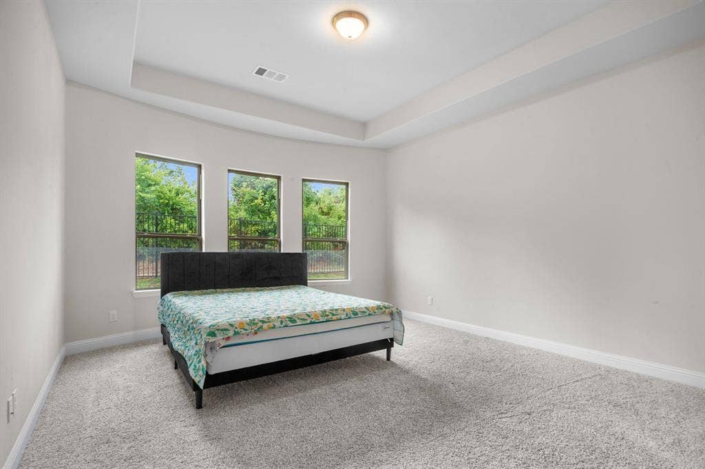 16050 Talamore Lane, Frisco, TX 75035 Carpeted bedroom featuring multiple windows and a raised ceiling