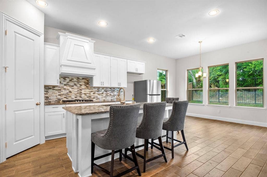 16050 Talamore Lane, Frisco, TX 75035 Kitchen featuring a center island with sink, light hardwood / wood-style flooring, premium range hood, stainless steel appliances, and white cabinetry