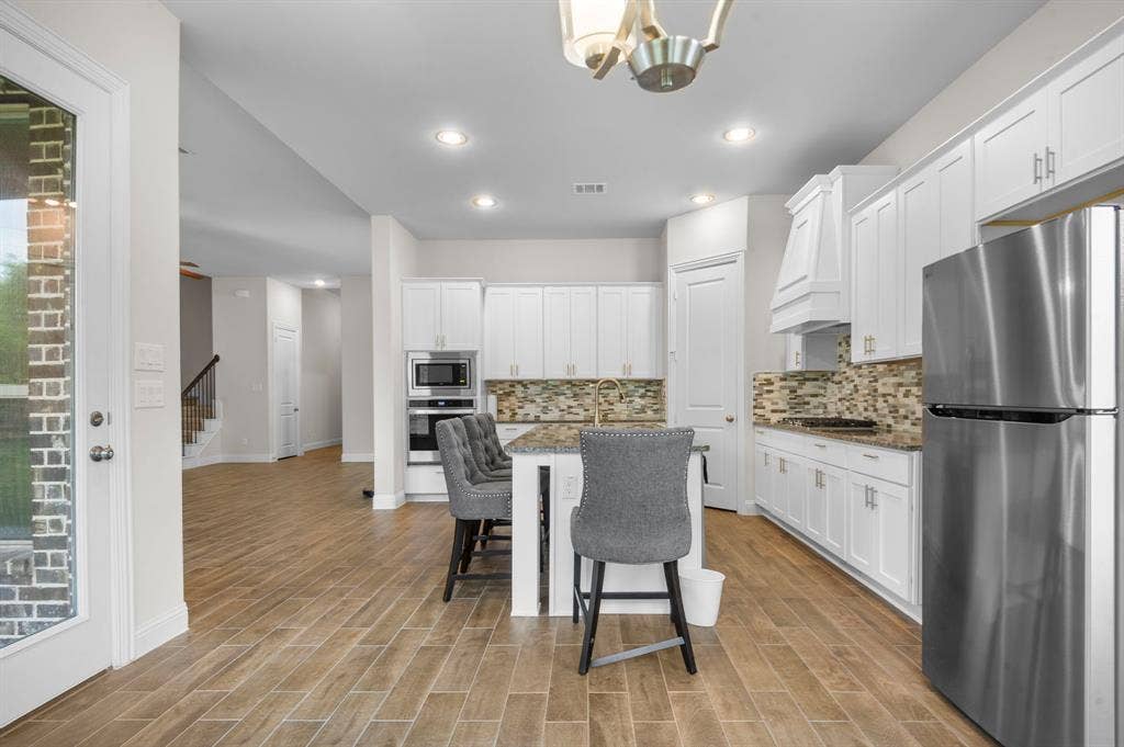 16050 Talamore Lane, Frisco, TX 75035 Kitchen with stone counters, appliances with stainless steel finishes, and white cabinetry