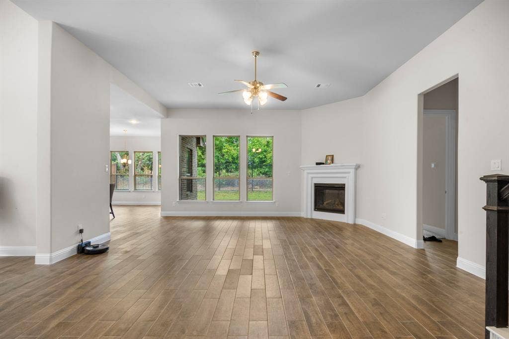 16050 Talamore Lane, Frisco, TX 75035 Unfurnished living room featuring ceiling fan and dark hardwood / wood-style floors