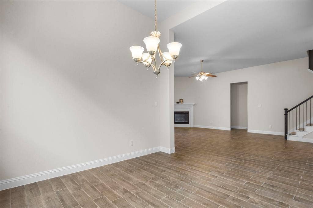16050 Talamore Lane, Frisco, TX 75035 Unfurnished living room featuring light wood-type flooring and ceiling fan with notable chandelier