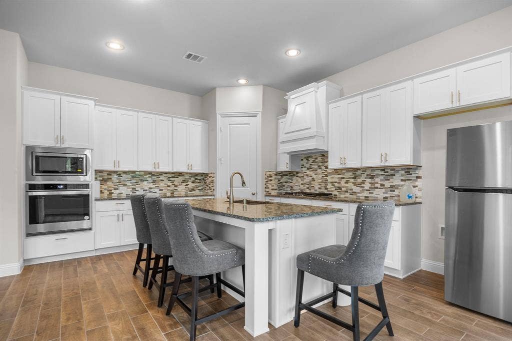 16050 Talamore Lane, Frisco, TX 75035 Kitchen with stainless steel appliances, sink, white cabinetry, and a kitchen island with sink
