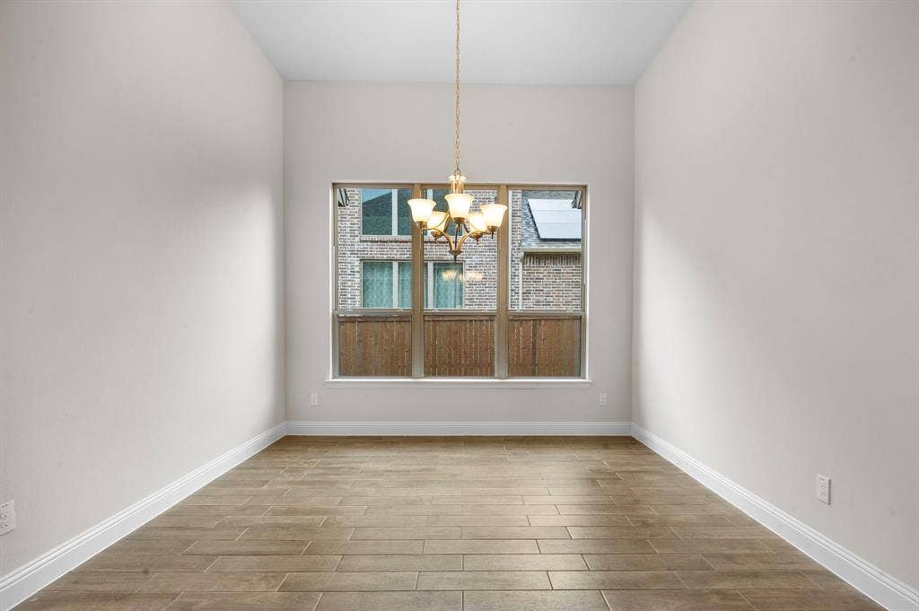16050 Talamore Lane, Frisco, TX 75035 Unfurnished dining area with a healthy amount of sunlight, wood-type flooring, and a chandelier