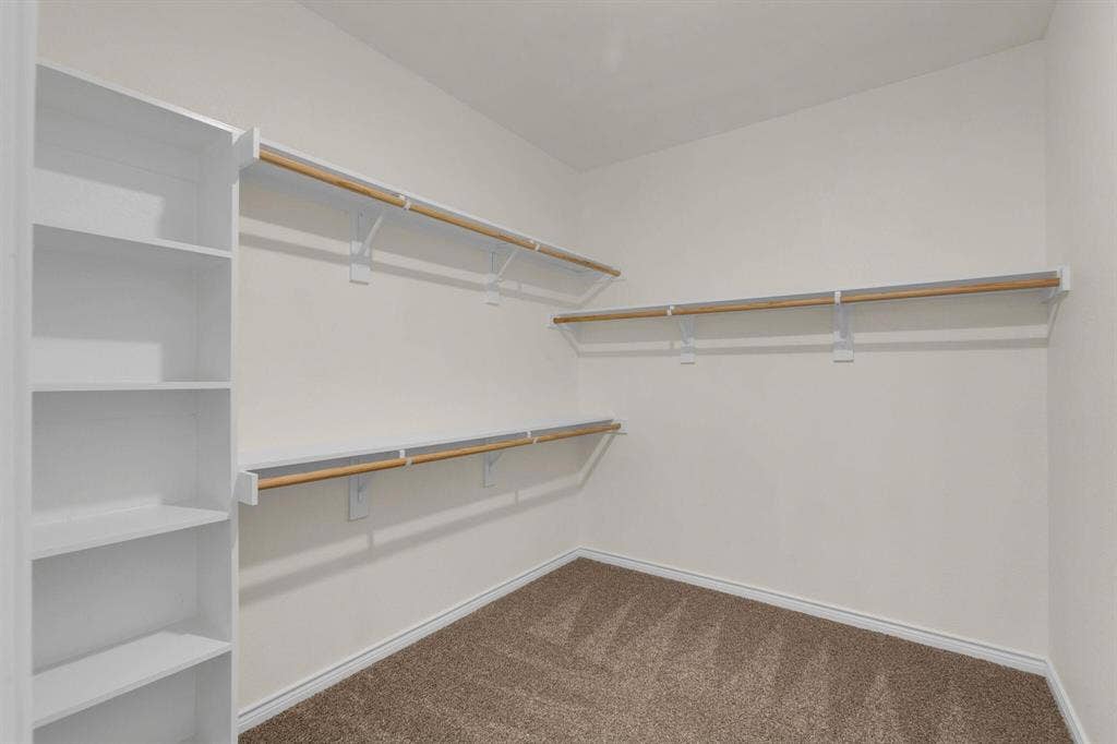 3106 Maverick Drive, Heath, TX 75126 Spacious walk-in closet featuring built-in shelving, multiple hanging rods, and light-toned carpet flooring