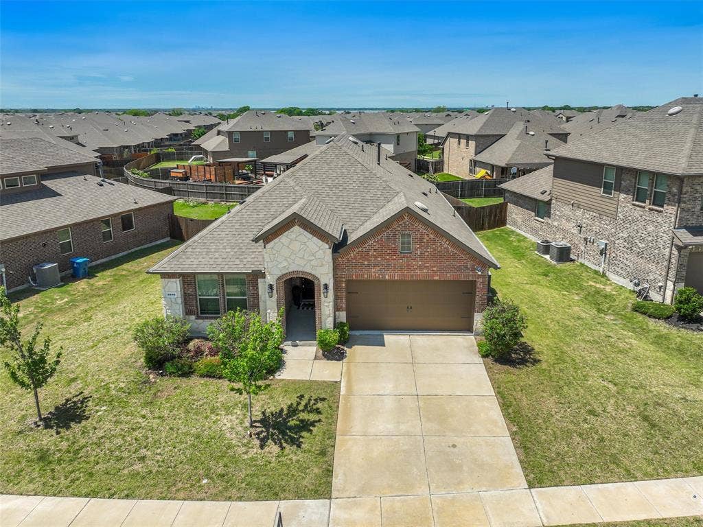 3106 Maverick Drive, Heath, TX 75126 Charming brick-front home featuring a two-car garage, manicured front lawn with established landscaping, concrete driveway, and arched entryway