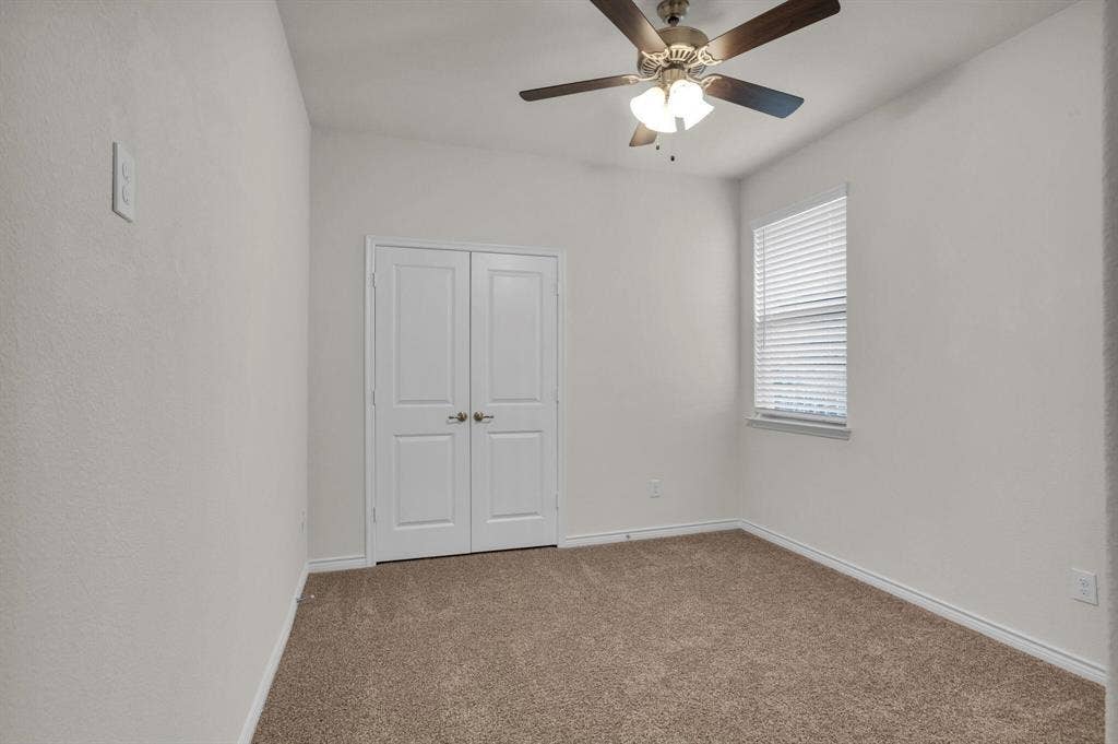 3106 Maverick Drive, Heath, TX 75126 Neutral toned bedroom featuring brown carpeting, a window with horizontal blinds, white double doors, and a ceiling fan with integrated lighting