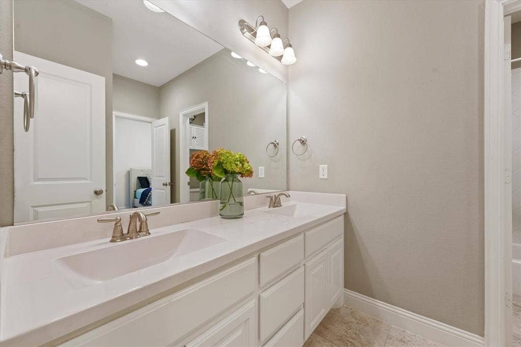 1113 5th Street, Argyle, TX 76226 Full secondary bathroom with dual sinks, white cabinetry, large mirror and separate access to the tub and shower area.