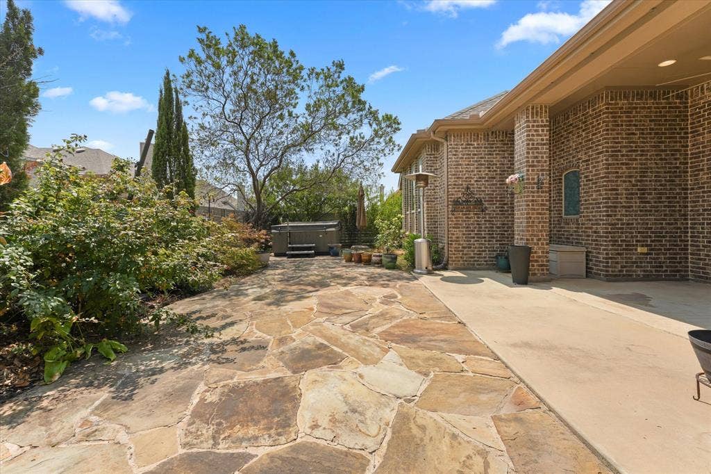 1113 5th Street, Argyle, TX 76226 Private backyard featuring an extended flagstone patio, mature landscaping, hot tub and multiple areas for outdoor enjoyment.