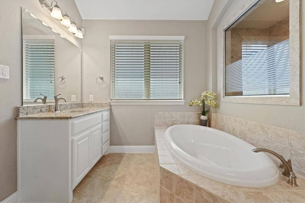 1113 5th Street, Argyle, TX 76226 Relaxing soaking tub surrounded by tile, positioned beneath a large window with natural light and adjacent to the walk-in shower.