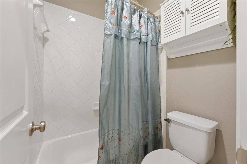 1113 5th Street, Argyle, TX 76226 Secondary bathroom with tiled tub and shower combination, built-in storage and neutral finishes.