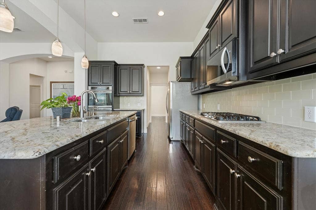 1113 5th Street, Argyle, TX 76226 Spacious kitchen with granite countertops, gas cooktop, subway tile backsplash, stainless steel appliances and abundant cabinet storage.
