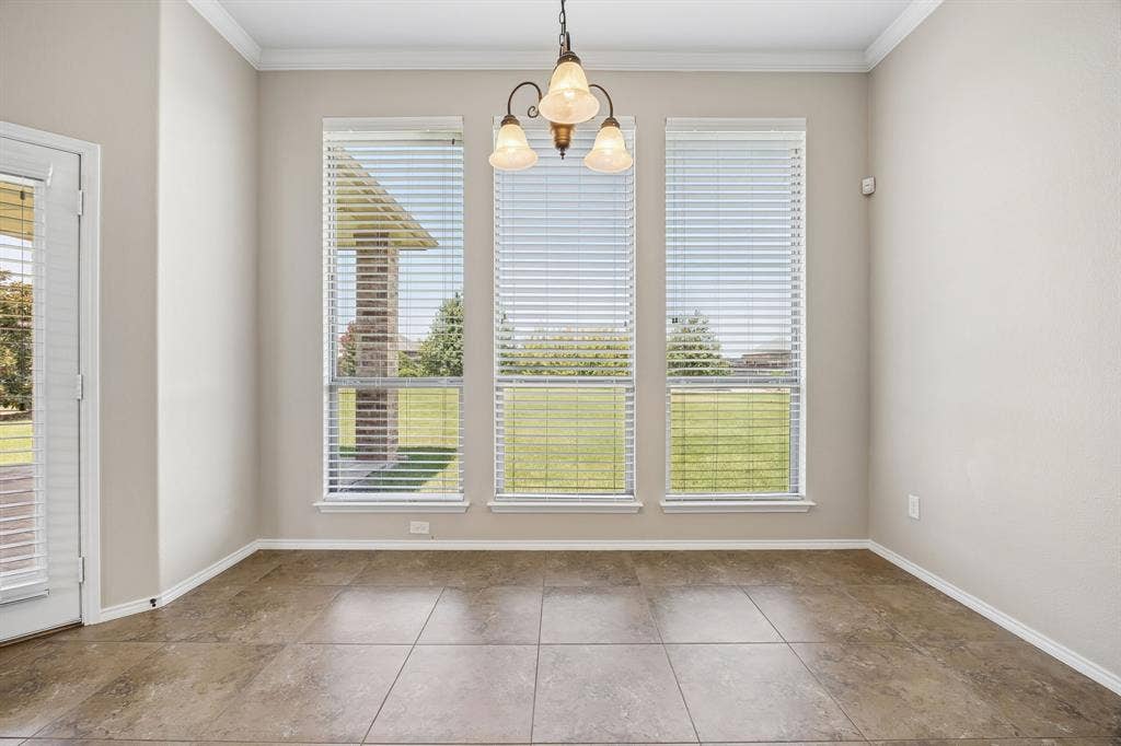The bright breakfast area that's open to the kitchen and living room has elegant crown molding and a wall of oversized windows that flood the space with natural light while overlooking the expansive backyard.