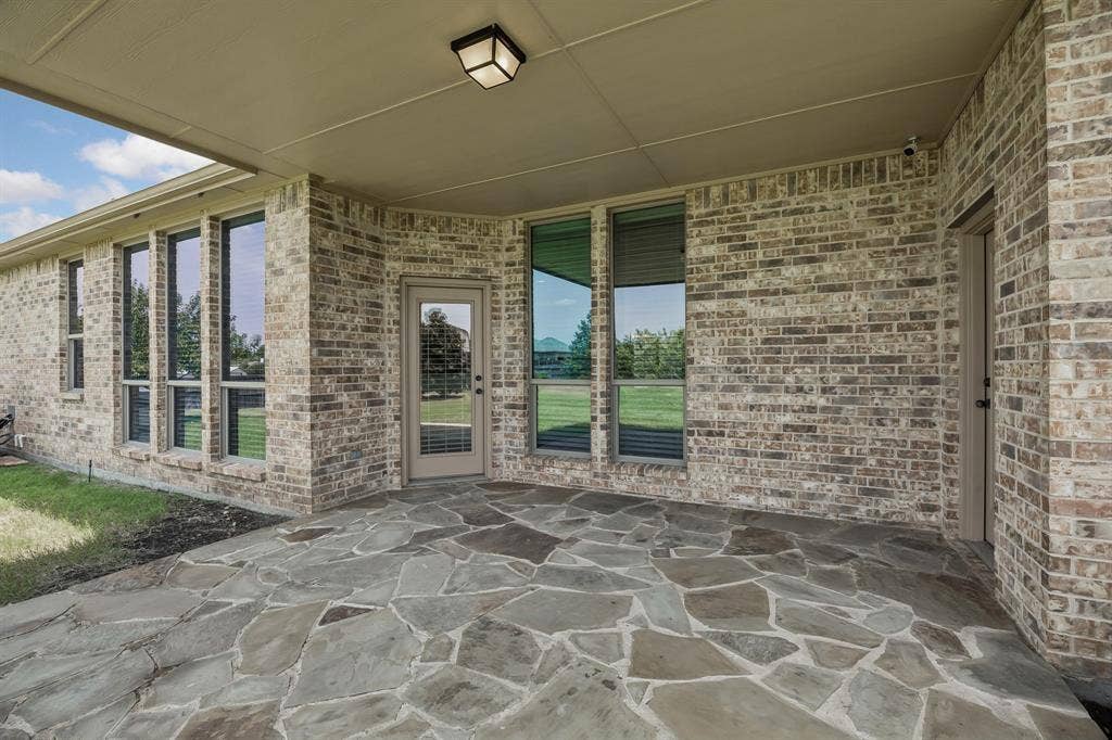Covered outdoor living space with attractive flagstone flooring has direct access to the primary suite, breakfast area/living room and the backyard—perfect for relaxing or hosting guests year-round.