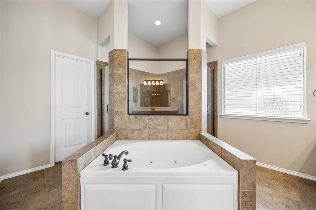 Relax in the oversized jetted soaking tub, perfectly positioned between separate vanities and dual walk-in shower for a true spa-like experience.