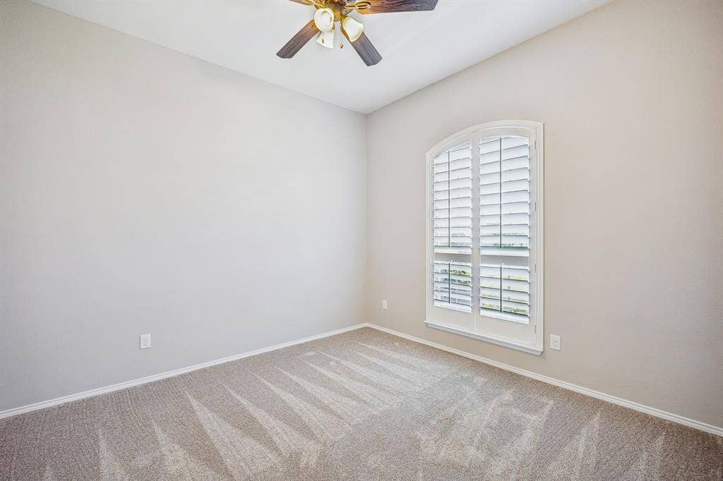 Another bright secondary bedroom offers abundant natural light, plantation shutters, and a peaceful retreat for family or visitors.