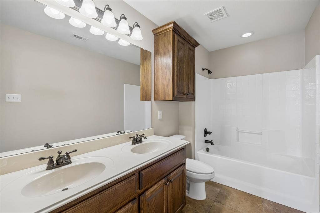 The spacious guest bath features dual sinks, abundant cabinetry, and a full tub/shower combination, making busy mornings a breeze.