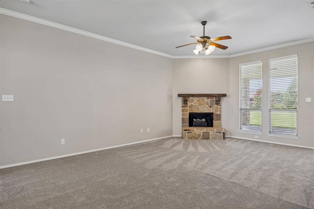 The expansive living room offers endless possibilities for entertaining, highlighted by a stunning stone fireplace and elegant crown molding.