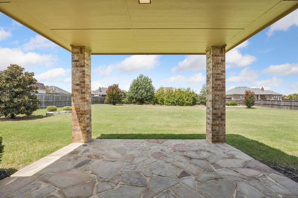The covered patio creates the perfect extension of the home, offering shaded outdoor living with beautiful views across the expansive backyard.