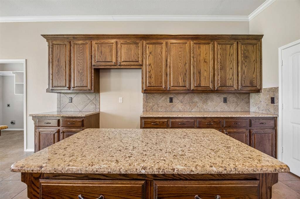 Large center island provides additional workspace, seating, and storage, complemented by extensive cabinetry and generous countertop space throughout.