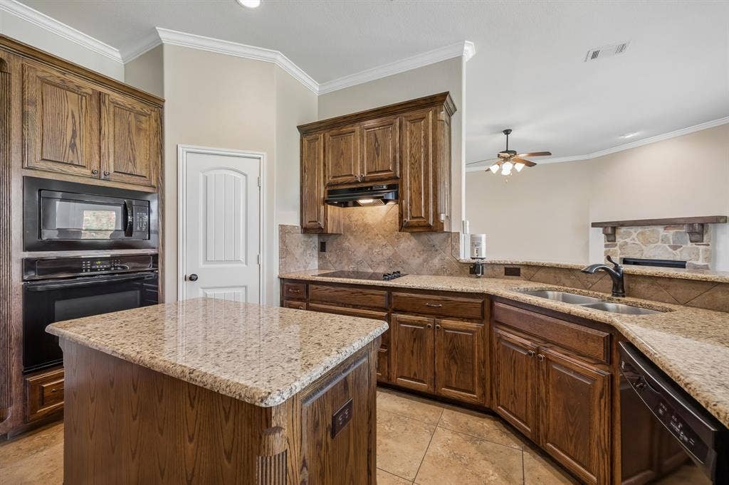 Beautiful kitchen showcasing granite countertops, custom cabinetry, electric cooktop, double sink overlooking the living area, and an open-concept design perfect for everyday living.