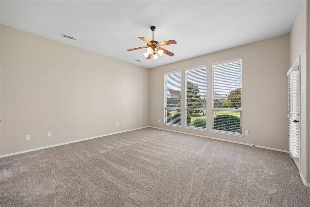 Escape to your oversized primary suite with soaring ceilings, plush carpeting, and a wall of windows overlooking the beautifully landscaped backyard.