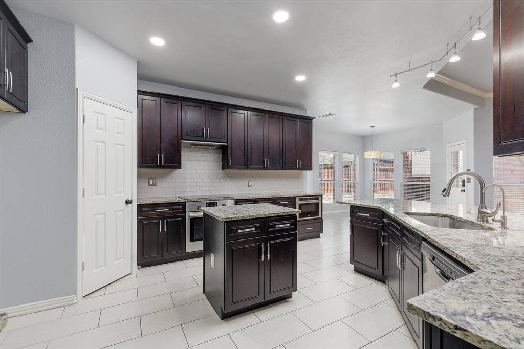 1913 Abilene Way, McKinney, TX 75072 Kitchen featuring dark wood cabinetry, granite countertops, subway tile backsplash, and stainless steel appliances