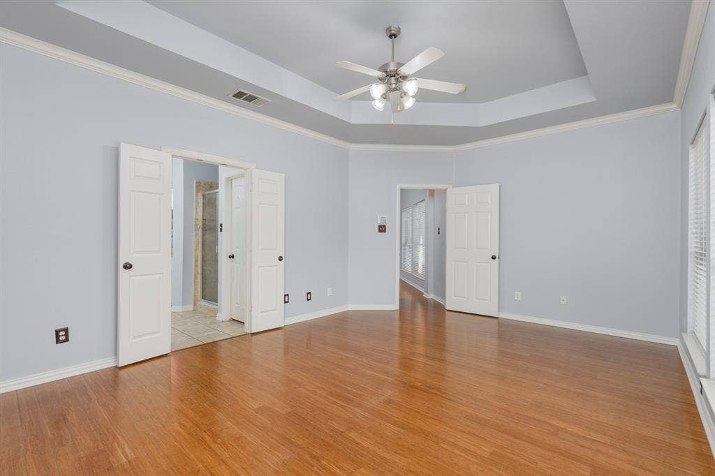 1913 Abilene Way, McKinney, TX 75072 Spacious room featuring wood-finish flooring, a tray ceiling with crown molding, and a ceiling fan with integrated lighting