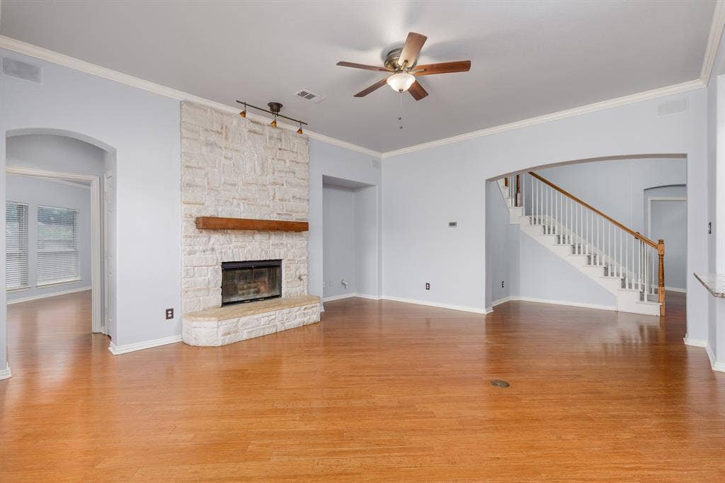 1913 Abilene Way, McKinney, TX 75072 Spacious living area featuring a stone-clad fireplace with a wood mantel, wood-finish flooring, and crown molding