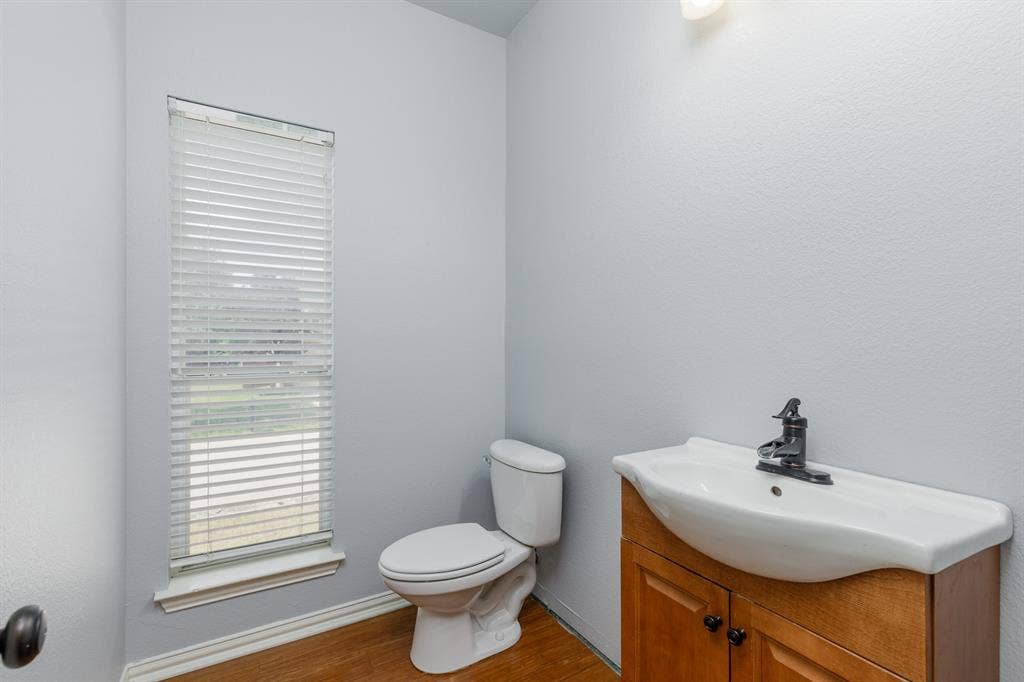 1913 Abilene Way, McKinney, TX 75072 Compact half bath featuring a two-piece toilet with elongated bowl, wood-finish vanity cabinet with undermount sink and chrome hardware, and single-handle faucet
